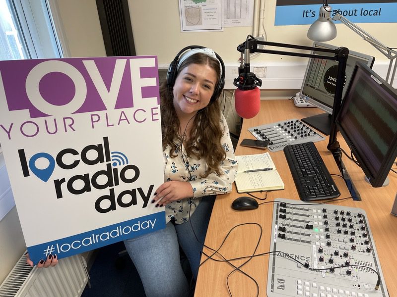 Presenter holds Local Radio Day sign